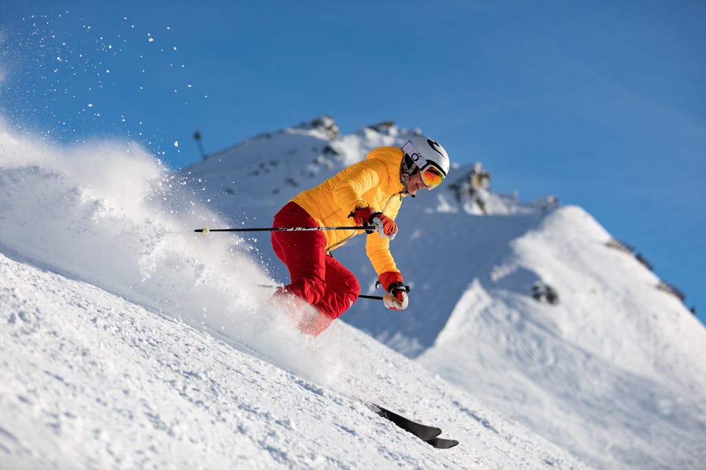 Dynamic capture of a skier racing downhill in snowy mountains, showcasing adrenaline and winter sport excitement.