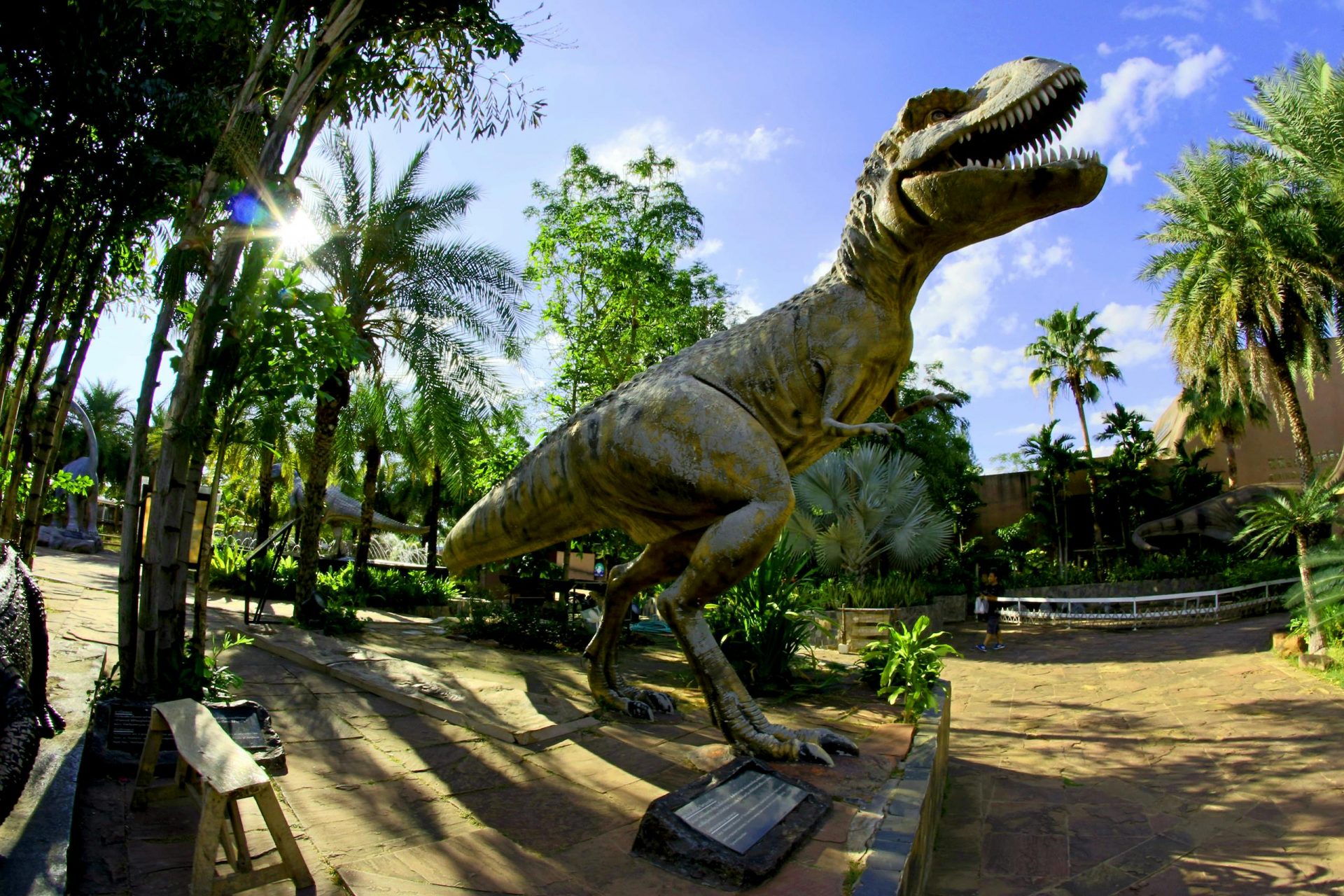 Life-sized Tyrannosaurus Rex statue in a lush tropical park, perfect for outdoor dinosaur exhibits.