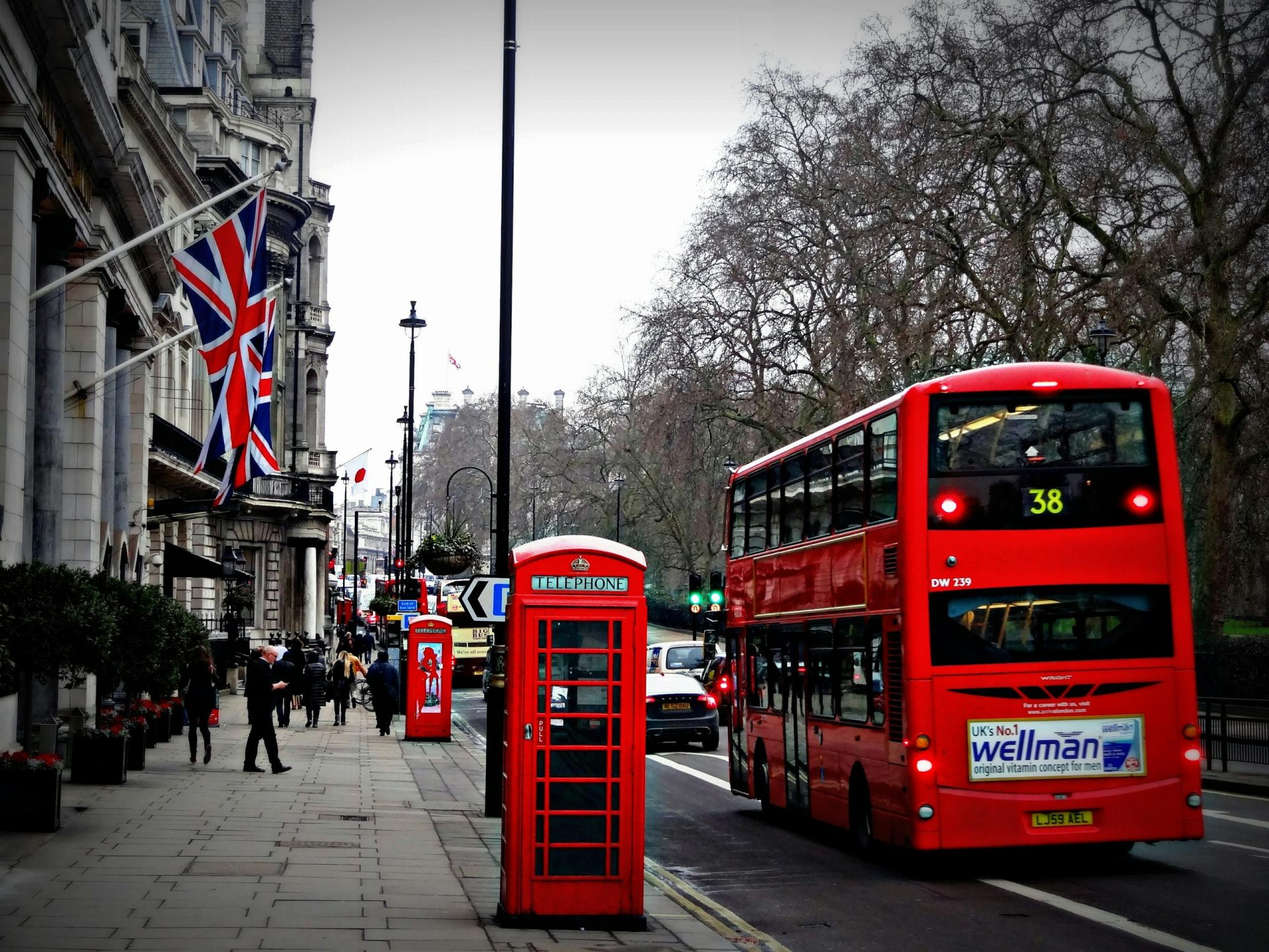 Classic London scene featuring a red double-decker bus and iconic phone booth on a busy city street.