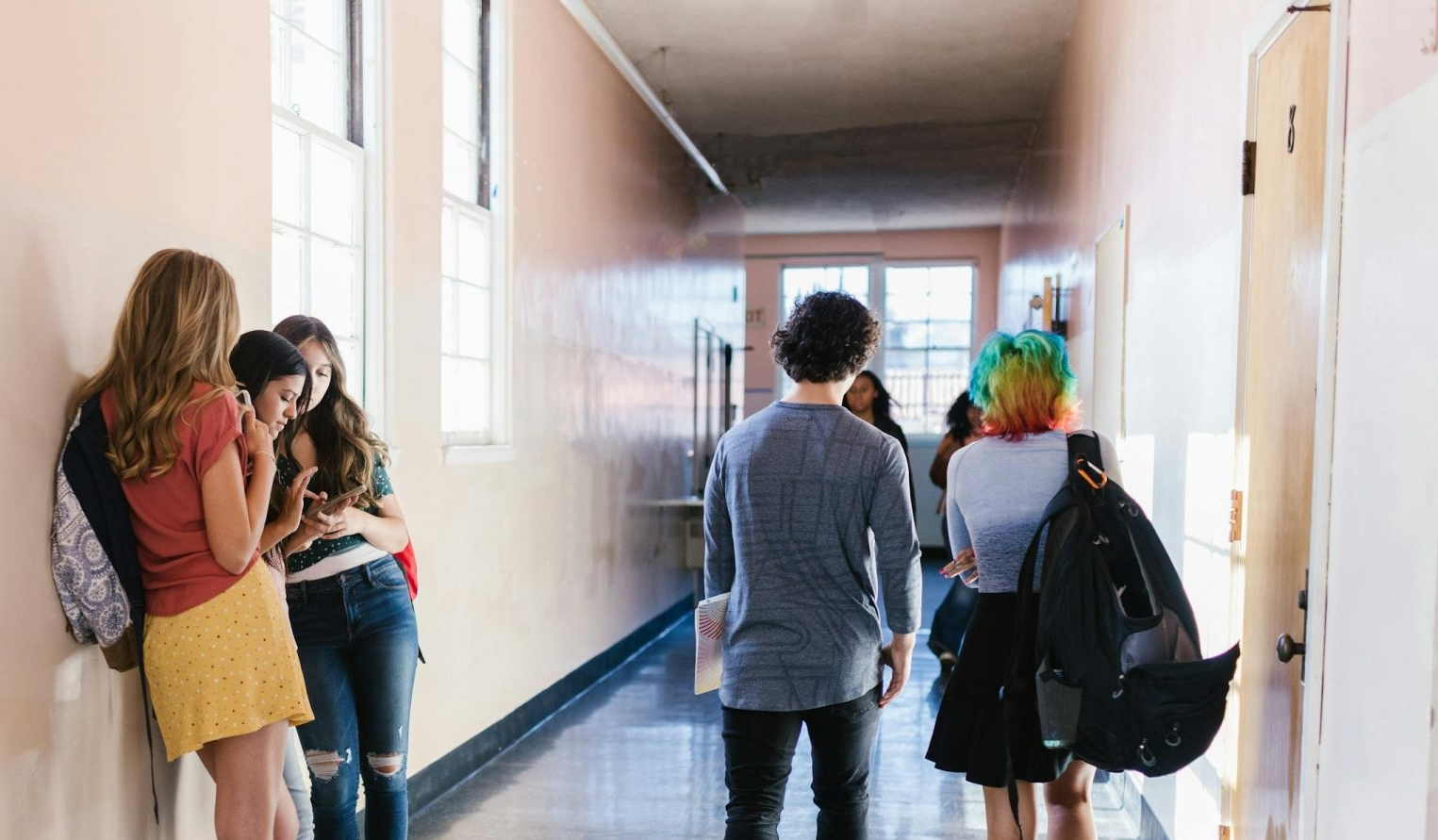 Group of teenagers interacting in a bright school hallway, showcasing diversity and everyday school life.